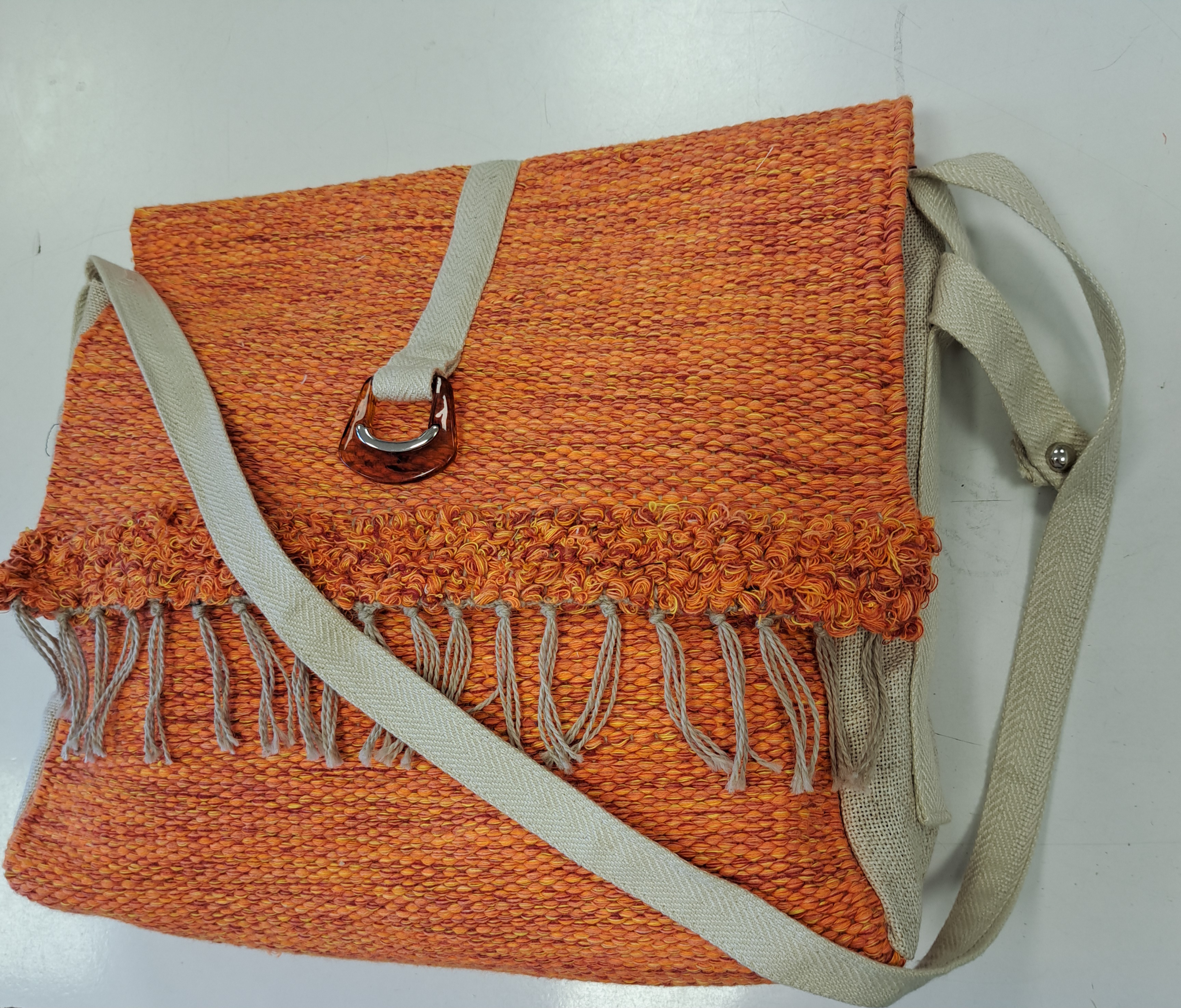 Orangefarbene, handgefertigte Umhängetasche  mit Fransen und Schnalle, hergestellt aus recycelten Materialien von unseren Nutzern