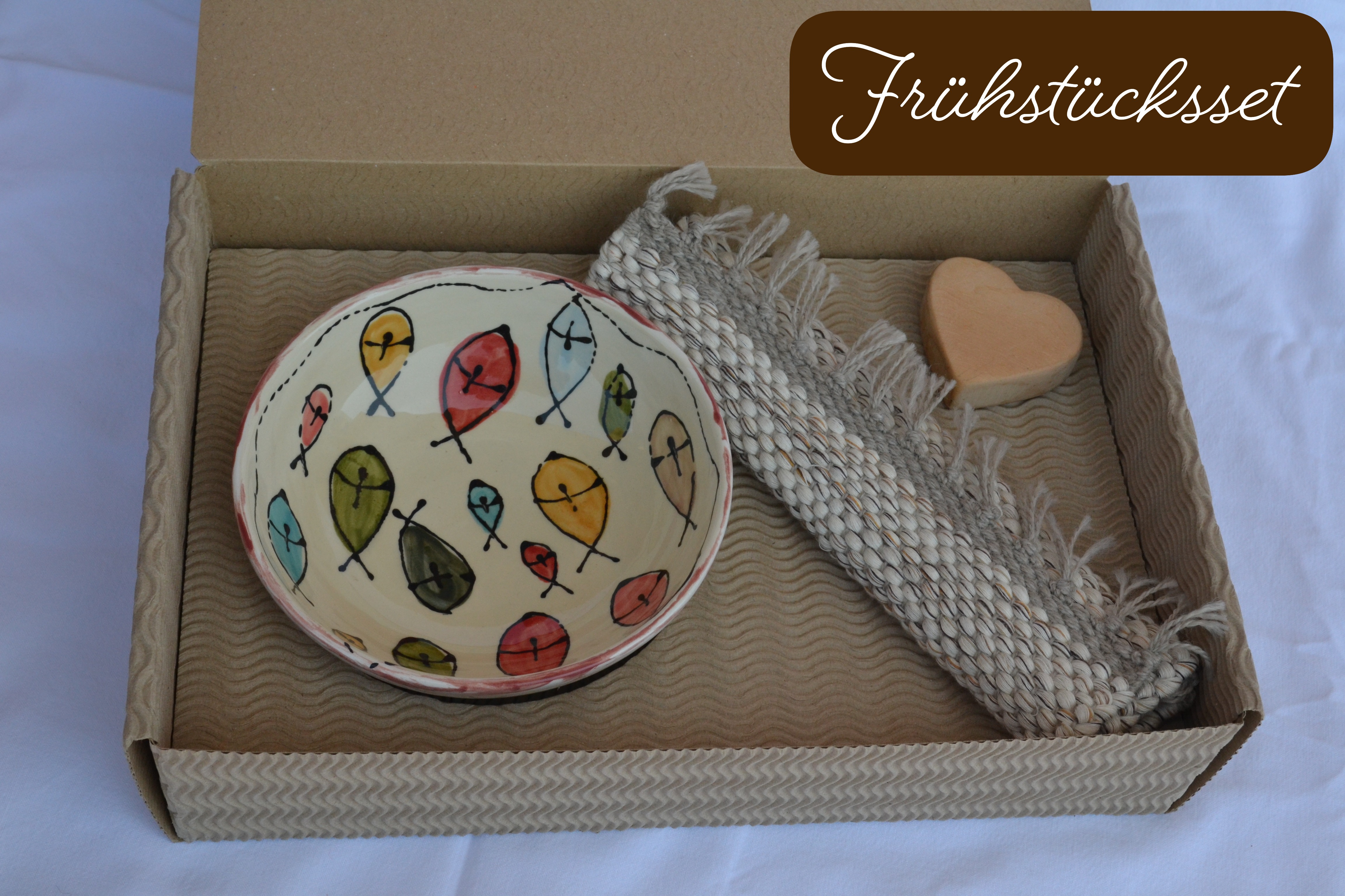 Handgemachtes Frühstücks-Set: Keramikschale mit bunten Fischen dekoriert, Teppich aus recyceltem Stoff und herzförmige Seife, verpackt in einem Karton