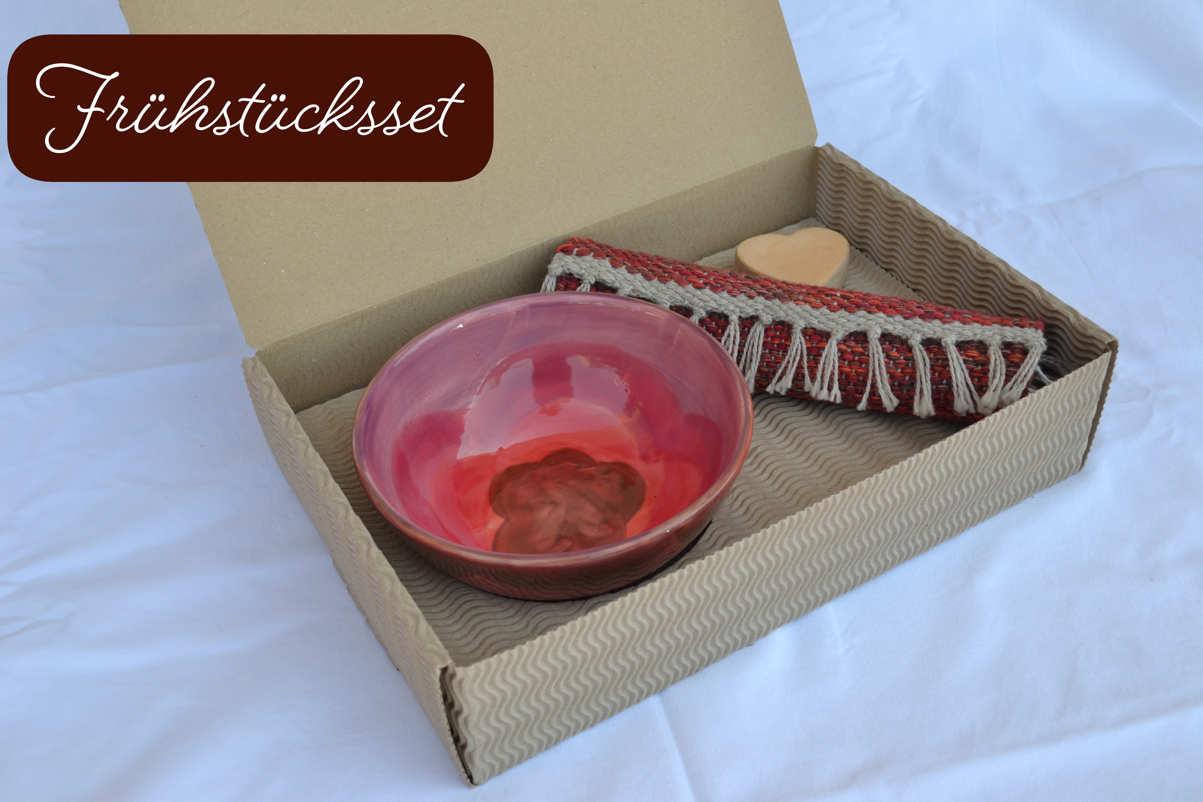Handgemachtes Frühstücks-Set in einem Karton, mit einer roten Schale und einem Teppich aus recyceltem Stoff